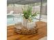 Outdoor dining table, set with pitcher, glasses and lemons, overlooking the pool at 2300 Stratford Dr, Sarasota, FL 34232