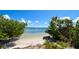 Secluded beach access framed by lush greenery, offering a peaceful view of the serene Gulf waters at 2402 16Th W St, Palmetto, FL 34221