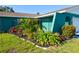 Lush landscaping featuring vibrant greenery, a small palm tree, and colorful flowers around the home at 2402 16Th W St, Palmetto, FL 34221