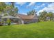 Spacious backyard with green lawn, mature trees, and a screened in pool at 3021 Leila Estelle Dr, Plant City, FL 33565