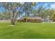 Well-manicured front lawn with brick home and majestic oak trees and foliage at 3021 Leila Estelle Dr, Plant City, FL 33565