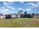 Rear exterior view of a two-tone home with a well-maintained lawn, offering a serene and inviting outdoor space at 3095 Pinetree St, Port Charlotte, FL 33952