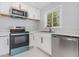 Bright kitchen featuring stainless steel appliances, white cabinetry, modern countertops, and natural light from a window at 3095 Pinetree St, Port Charlotte, FL 33952