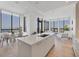 Open-concept kitchen with island seating, white cabinetry, and expansive windows showcasing cityscape views at 33 S Palm Ave # 1702, Sarasota, FL 34236