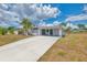 Single story house features a long driveway, carport and freshly painted exterior with tropical landscaping at 3599 Bali Dr, Sarasota, FL 34232