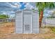 Durable shed offering convenient storage in the backyard, complemented by a charming palm tree and white fence at 3599 Bali Dr, Sarasota, FL 34232