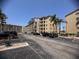 View of the tan building featuring multiple floors, palm trees, and plenty of parking spaces at 3647 Lake Bayshore Dr # 416, Bradenton, FL 34205