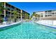 Large, sparkling community pool with lounge chairs, umbrellas, and nearby condominium buildings at 3647 Lake Bayshore Dr # 416, Bradenton, FL 34205