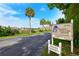Community entrance sign with lush landscaping and palm trees, denoting a 55+ condominium community at 3647 Lake Bayshore Dr # 416, Bradenton, FL 34205