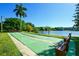 Outdoor shuffleboard courts with benches, set against a serene lakeside backdrop with palm trees at 3647 Lake Bayshore Dr # 416, Bradenton, FL 34205
