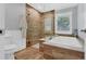 Elegant bathroom featuring a soaking tub and separate glass-enclosed shower with wood-look tile and a shuttered window at 425 46Th Nw St, Bradenton, FL 34209