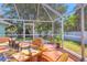 Outdoor dining area with wicker chairs inside a screened patio offering views of the landscaped yard at 425 46Th Nw St, Bradenton, FL 34209