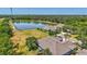 Scenic aerial view of the property featuring a serene pond, well-maintained lawn, and lush tropical landscaping at 4740 105Th E Ave, Parrish, FL 34219
