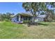 View of the home's exterior and screened-in porch overlooking a lush green lawn and mature landscaping at 4740 105Th E Ave, Parrish, FL 34219