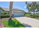 Side view of a house with landscaped yard, showing garage, driveway, and mature palm tree at 4740 105Th E Ave, Parrish, FL 34219