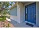Close-up of a blue front door with welcome mat, showing a covered entry and manicured landscaping at 4740 105Th E Ave, Parrish, FL 34219