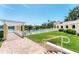 Community pool area with a pergola, lounge chairs, green grass and an adjacent body of water in the background at 4801 Osprey S Dr # 405, St Petersburg, FL 33711