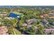 Aerial view of a community with a golf course and lake surrounded by buildings and mature trees at 5291 Willow Links # 54, Sarasota, FL 34235