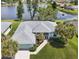 This aerial view showcases a home with a beautiful lake view, green lawn and mature palm trees at 5596 Sabal Trace Dr, North Port, FL 34287