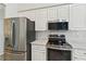 Modern kitchen with stainless steel appliances, white cabinets, and tile backsplash at 5596 Sabal Trace Dr, North Port, FL 34287