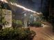 Charming home exterior featuring a brick walkway, lush landscaping, and inviting string lights for evening ambiance at 590 Artists Ave, Englewood, FL 34223