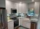 This kitchen features white cabinets, stainless appliances, and a white farmhouse style sink at 590 Artists Ave, Englewood, FL 34223