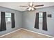 Cozy bedroom with a ceiling fan, two windows with black curtains, and neutral-colored carpet at 5905 Olive Ave, Sarasota, FL 34231