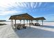Secluded beach picnic area with covered picnic tables on white sand with blue skies and tranquil waters in the background at 5966 Midnight Pass Rd # G-51 & G-58, Sarasota, FL 34242