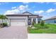 Well-manicured front yard with lush landscaping, a paved driveway, and a two-car garage at 6244 Talon Preserve Dr, Nokomis, FL 34275