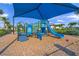 Colorful playground with a slide, climbing structure, and soft ground covering, under a shade canopy at 6244 Talon Preserve Dr, Nokomis, FL 34275