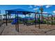 Community playground featuring swings and a slide under a shaded structure, perfect for outdoor fun at 6244 Talon Preserve Dr, Nokomis, FL 34275