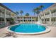 Community pool is surrounded by chairs and palm trees at 7100 Gulf Dr # 114, Holmes Beach, FL 34217