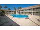 Community pool surrounded by lounge chairs and palm trees at 7100 Gulf Dr # 114, Holmes Beach, FL 34217