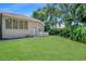 Backyard view showcasing a well-maintained lawn, neutral-toned exterior, and tropical landscaping at 104 Park Trace Blvd, Osprey, FL 34229