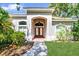 Elegant home entrance with a brick pathway, arched doorway, and well-maintained landscaping at 104 Park Trace Blvd, Osprey, FL 34229