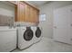 Functional laundry room features tiled floors, washer, dryer, cabinetry and a sink at 104 Park Trace Blvd, Osprey, FL 34229