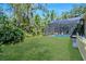 A screened-in pool sits amidst a backdrop of lush greenery, adjacent to a spacious grassy yard at 104 Park Trace Blvd, Osprey, FL 34229