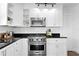 Well-lit kitchen featuring stainless steel appliances, white cabinets, black countertops, and subway tile backsplash at 1140 Oak Ne St, St Petersburg, FL 33701