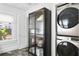 Modern laundry room featuring stacked washer and dryer, storage cabinet, and natural light at 1140 Oak Ne St, St Petersburg, FL 33701