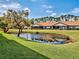 Charming home featuring a serene backyard pond reflecting the blue sky and manicured landscaping at 1211 Capri Isles Blvd # 26, Venice, FL 34292
