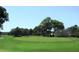 Golf course with lush green grass and mature trees. A red flag marks the hole at 1211 Capri Isles Blvd # 26, Venice, FL 34292