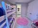 Bright bedroom with a bunk bed, pink rug, and a doorway leading to an ensuite bathroom at 16905 Sweetwater Village Dr, Bradenton, FL 34211