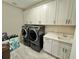 Laundry room with gray washer and dryer, white cabinets, and tile flooring at 16905 Sweetwater Village Dr, Bradenton, FL 34211