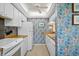 Quaint kitchen with white cabinets and appliances, complete with floral patterned wallpaper, sink and tile floors at 1703 Pelican Cove Rd # 356, Sarasota, FL 34231