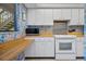 Cozy kitchen features white cabinetry, an oven, and a microwave with patterned floral wallpaper at 1703 Pelican Cove Rd # 356, Sarasota, FL 34231