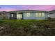 Wide shot of the home's backyard at dusk, featuring a screened lanai and green lawn at 17032 Harvest Moon Way, Bradenton, FL 34211