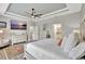 Open main bedroom featuring a large TV, tray ceilings, and access to kitchen and bath at 17032 Harvest Moon Way, Bradenton, FL 34211