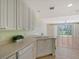 Bright kitchen with white cabinets, dishwasher, and view into the living room of the home at 1831 Burgos Dr, Sarasota, FL 34238