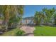 Landscaped backyard with brick path leading to a well-maintained lawn, tropical trees, and privacy fence at 1857 Jasmine Dr, Sarasota, FL 34239