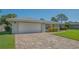 Charming single-story home with a brick driveway, two-car garage, and vibrant landscaping at 1857 Jasmine Dr, Sarasota, FL 34239